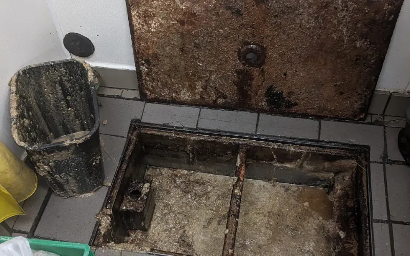 Grease trap pumping: a restaurant floor grease trap opened so the grease can be pumped out